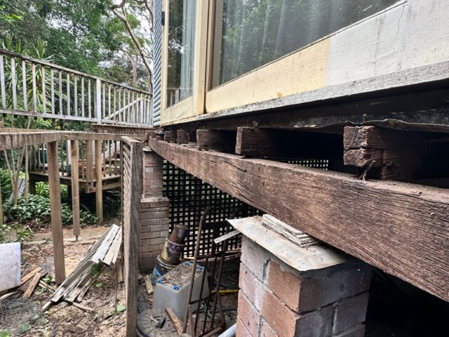 Weathered deck subfloor and bearer on brick piers beneath sliding glass door