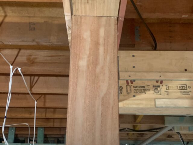 Laminated timber beam supported by hardwood post in renovation framing with exposed wiring.