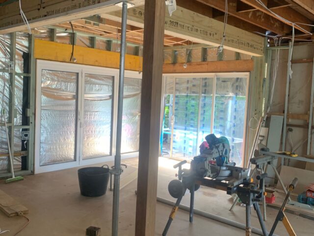 Home renovation with exposed timber framing, floor opening, sliding doors, and mitre saw.