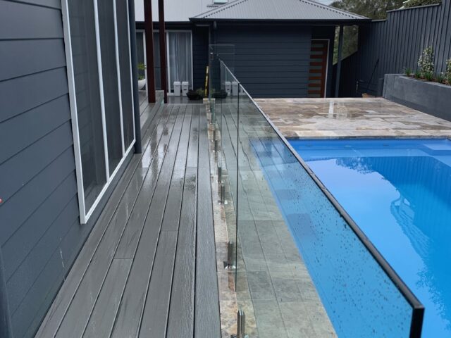 Composite deck beside frameless glass pool fence and tiled pool surround.