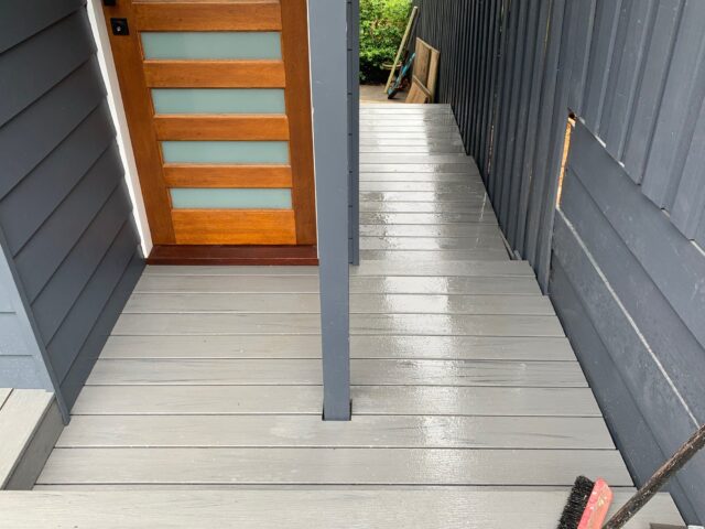 Wet grey composite decking side entry leading to timber door with frosted panels.