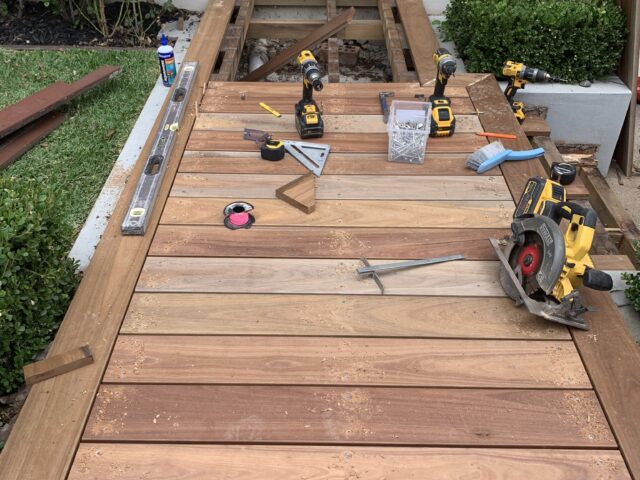Timber entry deck under construction with drills, circular saw and level near front steps.