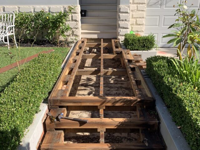 Front entry stairs and landing with exposed timber joists during deck replacement.