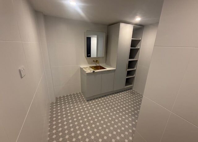 Renovated bathroom with star-pattern floor tiles, vanity and mirror cabinet, tall open shelves.
