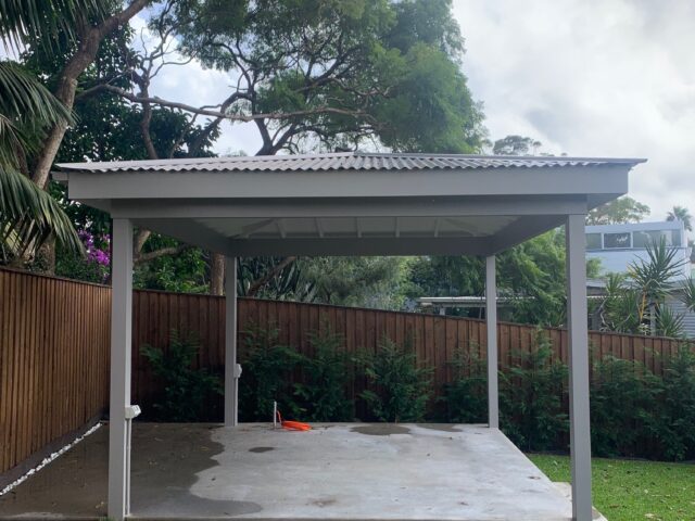 Freestanding backyard pergola with corrugated roof on new concrete slab, timber fence.
