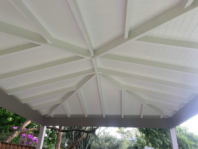 Underside of pitched pergola roof with white lining boards and exposed rafters.