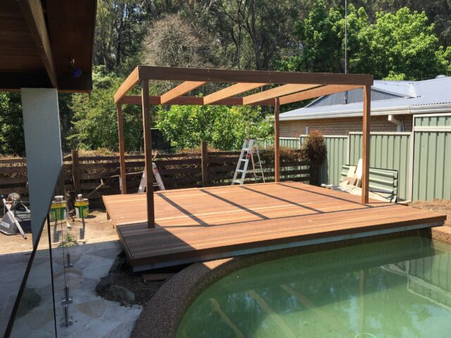 Timber poolside deck with pergola frame being built in backyard.