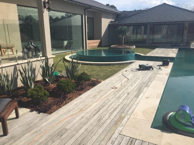 Timber pool deck with circular tiled spa, stone paving and landscaped garden.