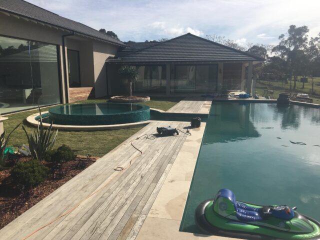 Timber decking beside large pool and circular spa, with new lawn and planting.