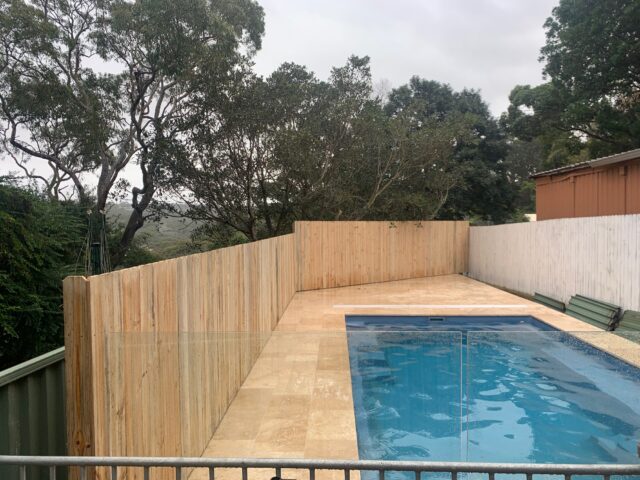 Backyard renovation with timber privacy fence, travertine paving and glass-fenced pool.