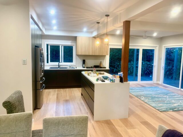 Contemporary kitchen renovation with island, timber floors and sliding glass doors to garden.
