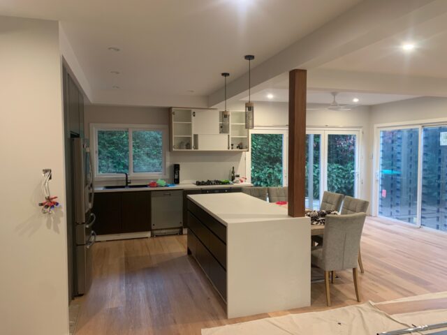 Open-plan kitchen renovation with white island, timber floors and sliding doors to garden.