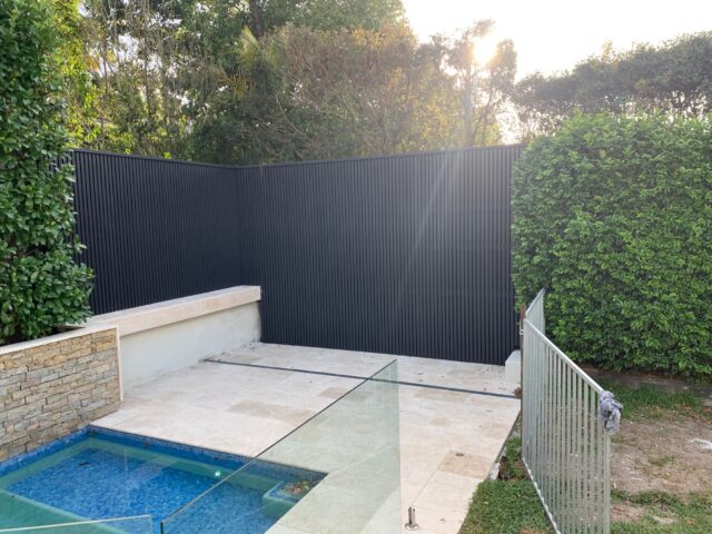 Poolside courtyard with black vertical slat fence, tiled terrace and glass balustrade