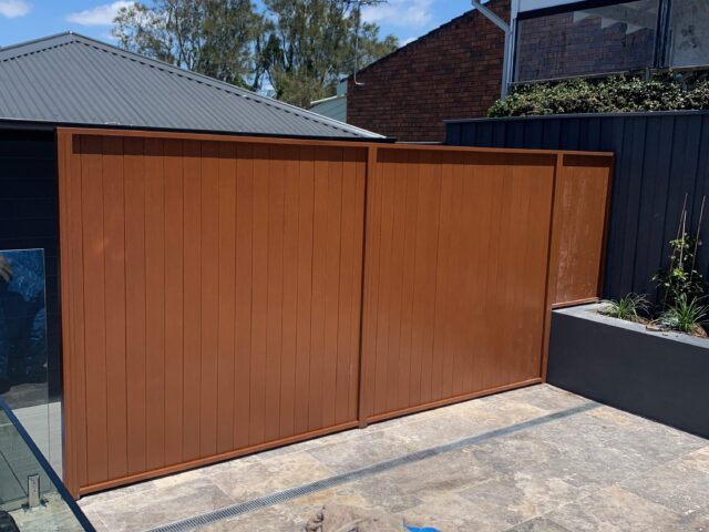 Timber privacy screen beside tiled courtyard, adjacent glass pool fence and raised planter.